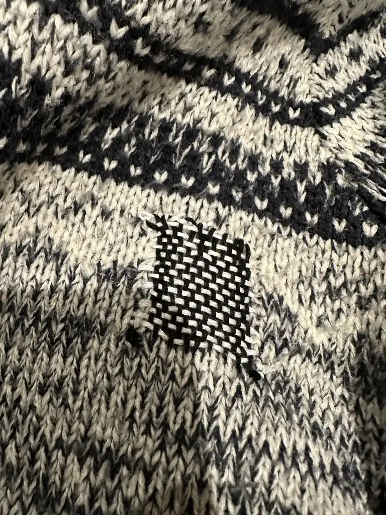 picture of a mended jumper, showing a weaved pattern